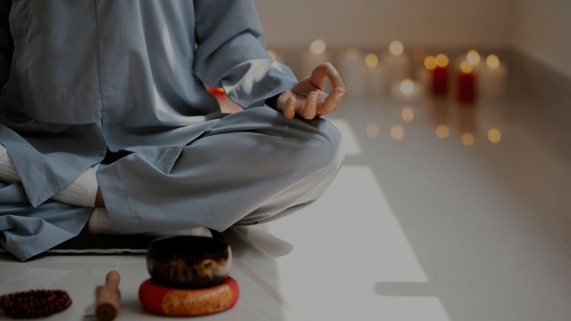  Person meditating in lotus pose with singing bowl and candles
