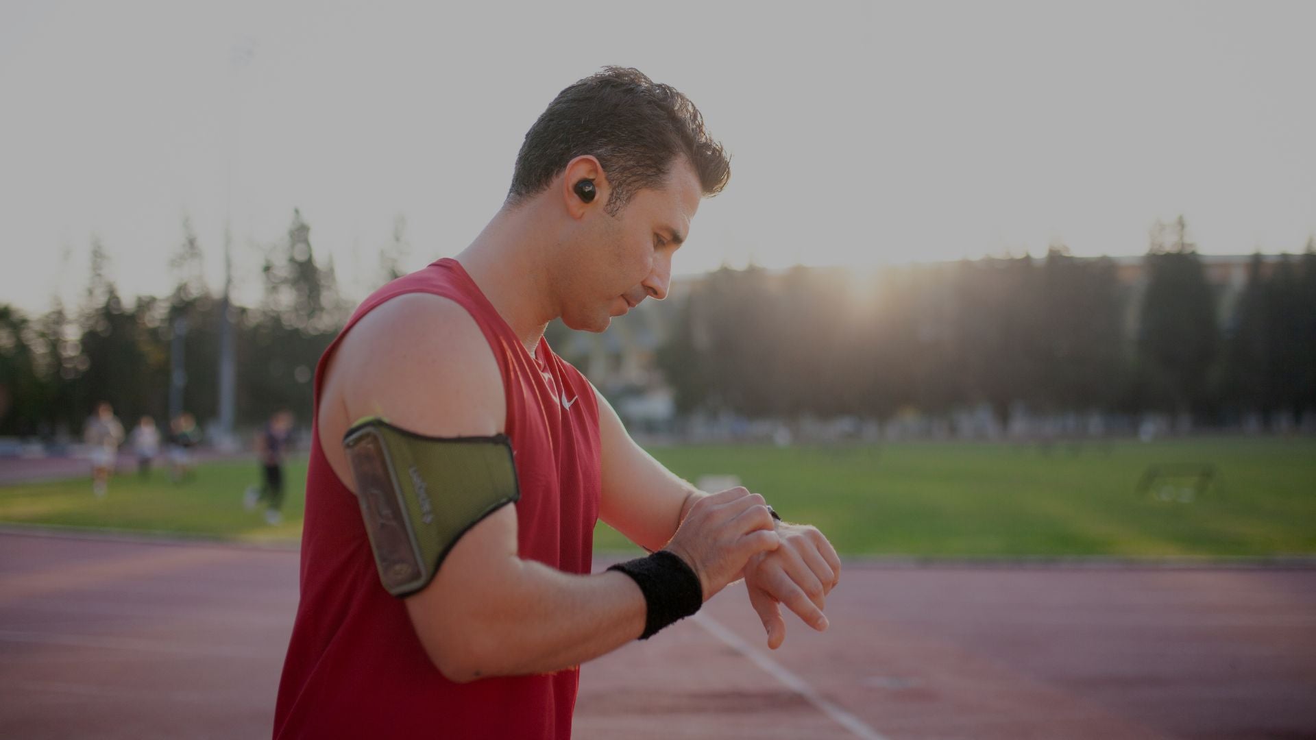 athletic man checking smartwatch during outdoor running workout at sunrise