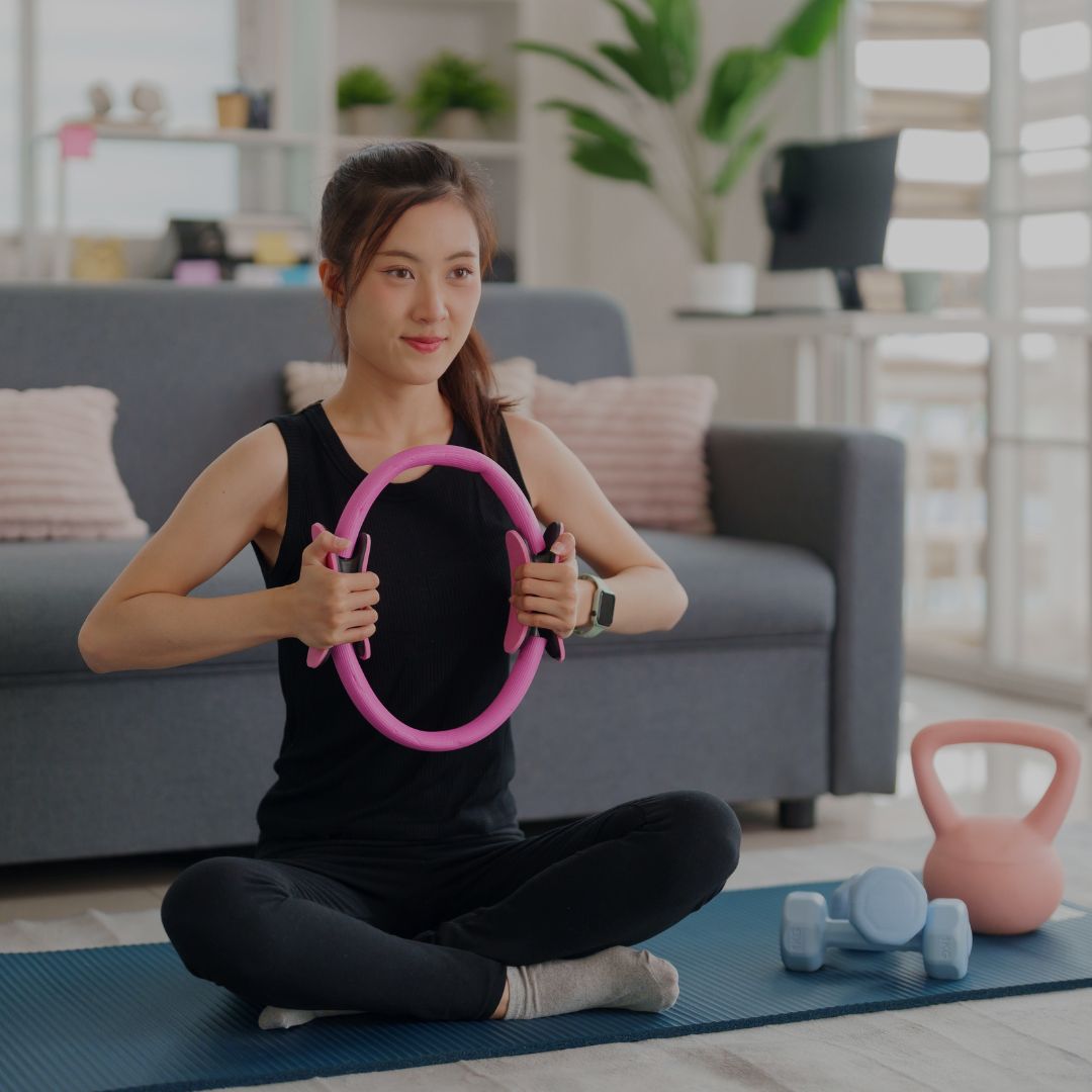 woman practicing home pilates workout with fitness ring and wellness accessories